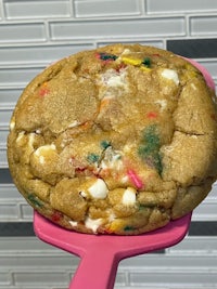 a cookie with sprinkles on top of a pink spatula